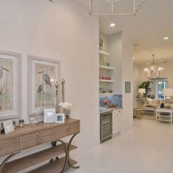 Entryway with a wooden console table, bird artwork, and view into a bright, open living and kitchen area.