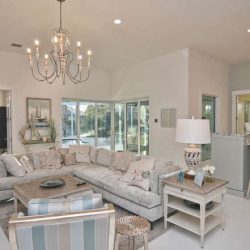 Spacious living room with a large sectional sofa, chandelier, breakfast bar, and sliding glass doors leading outside.
