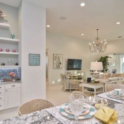 Open-concept living area with a modern kitchen, breakfast bar, and adjacent seating area featuring neutral decor.