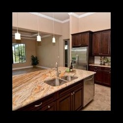 Modern kitchen with dark wood cabinets, stainless steel appliances, and a marble island with dual sinks and pendant lights.