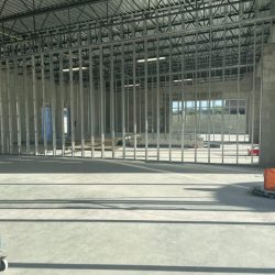 Interior of a commercial building under construction with exposed metal wall framing and concrete floor.