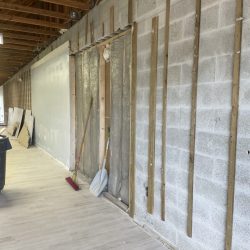 Partially finished interior wall with exposed studs, insulation, cleaning tools, and construction materials visible.